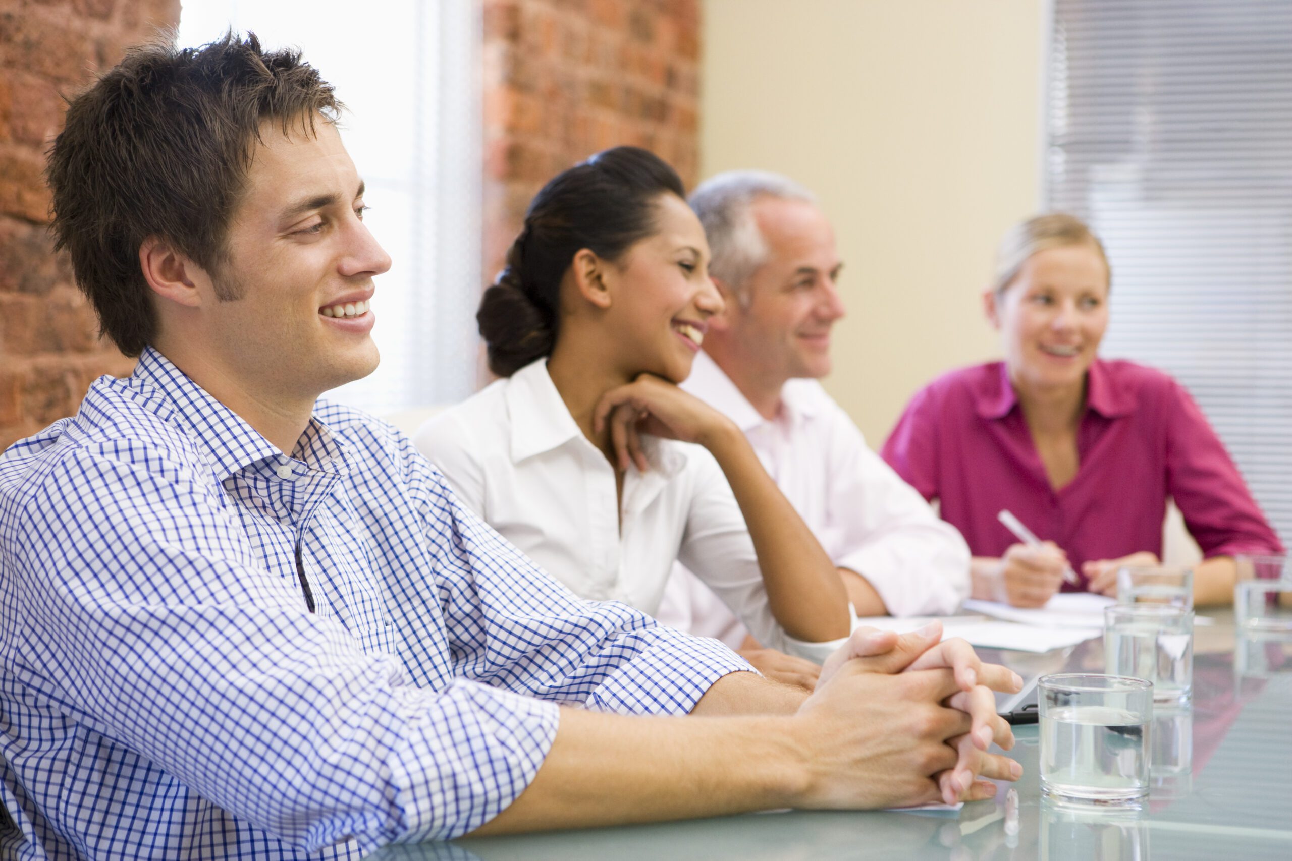 Happy employees sit at a conference table discussing relocation plans.