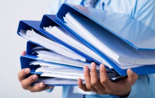Close-up of human hands holding a stack of folders with business documents on the foreground