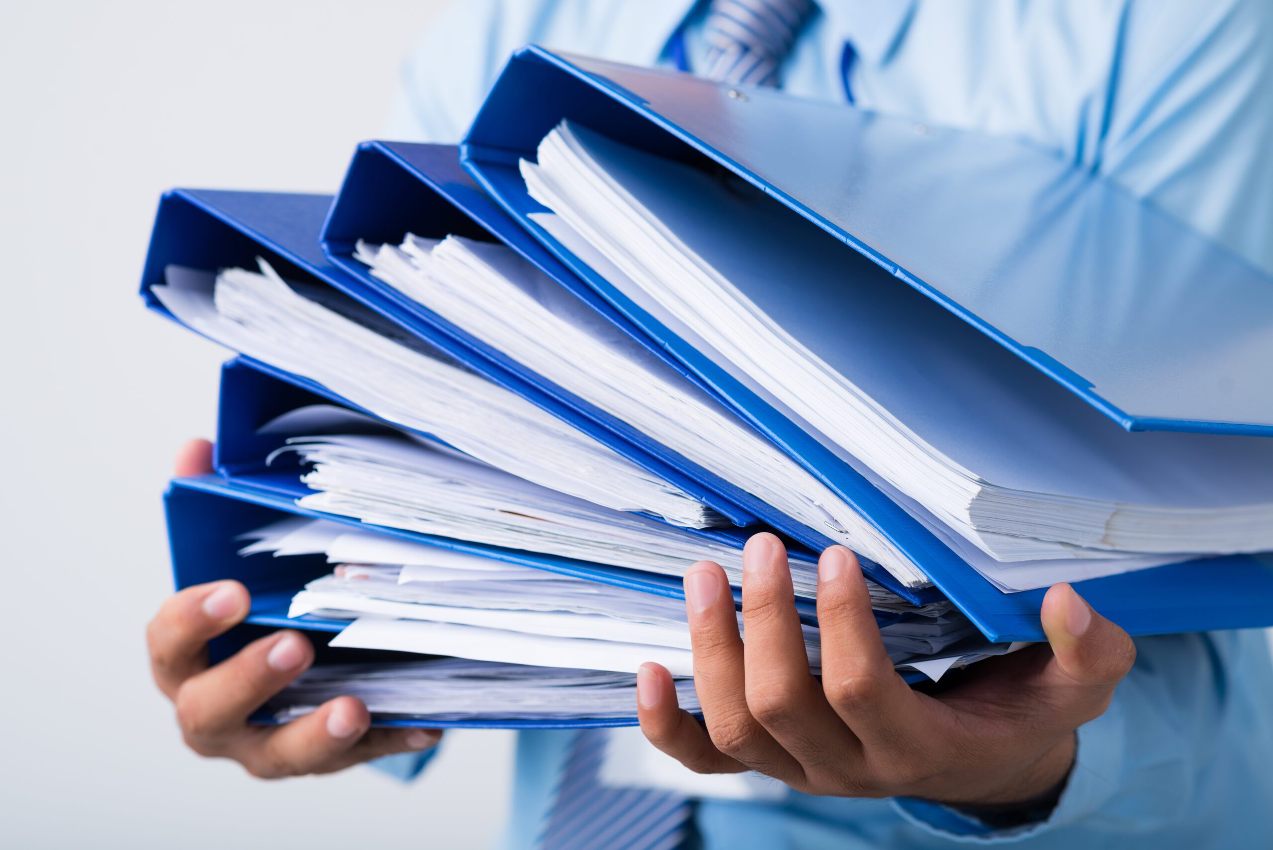 Close-up of human hands holding a stack of folders with business documents on the foreground