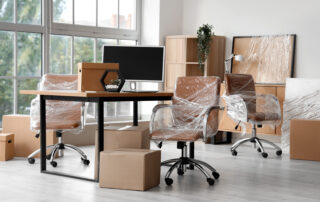 Interior of modern office with chairs wrapped in stretch film and cardboard boxes on moving day