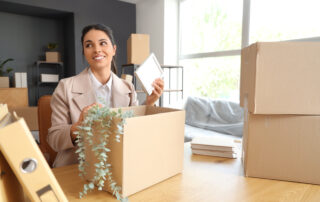 businesswoman packing frame into box in office on moving day
