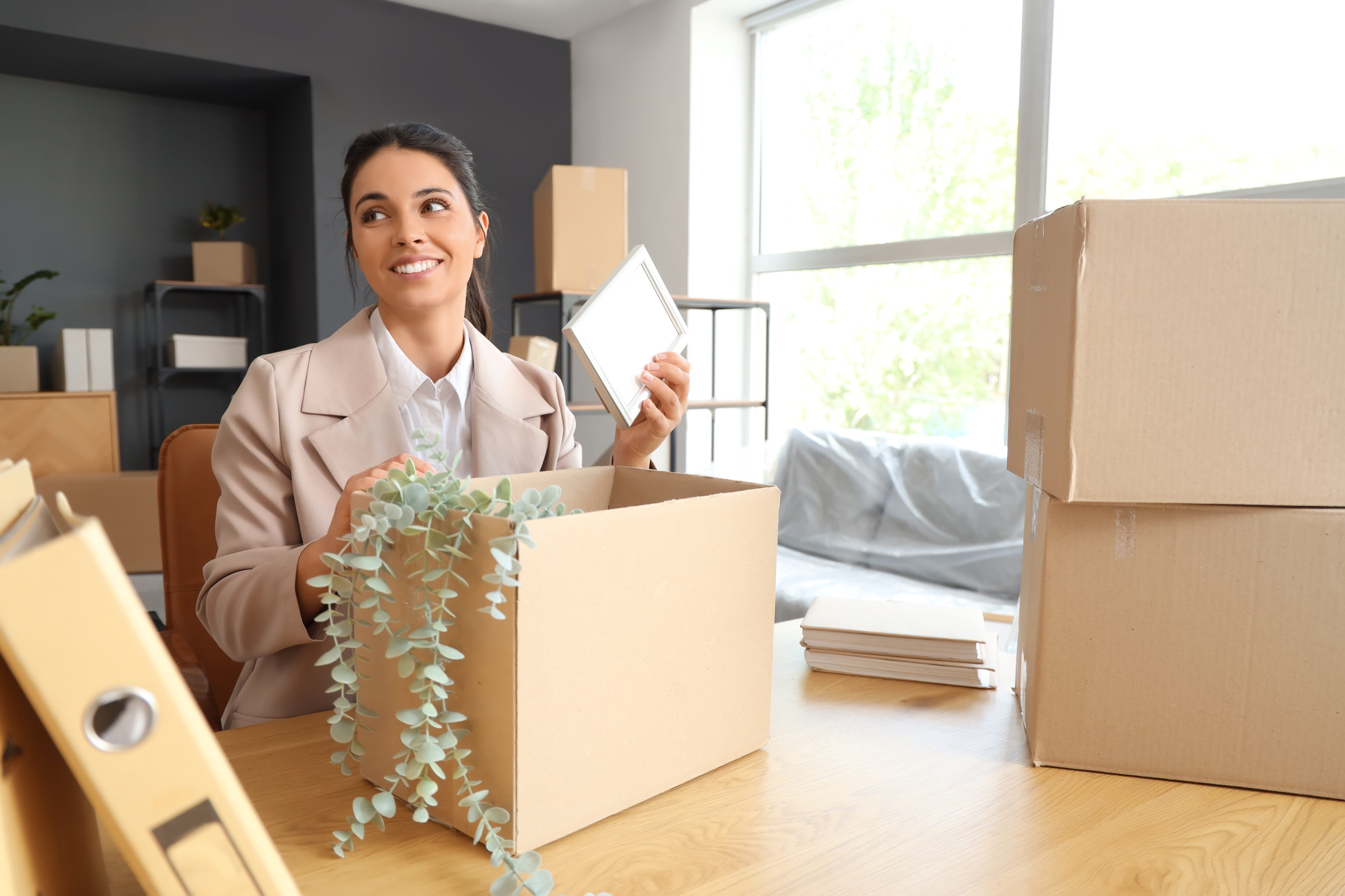 businesswoman packing frame into box in office on moving day