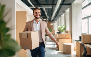 Businessman is moving to a new office. Holding a box of things in his hands.